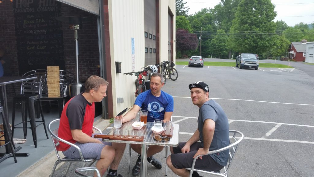 three men drink beer at outdoor table